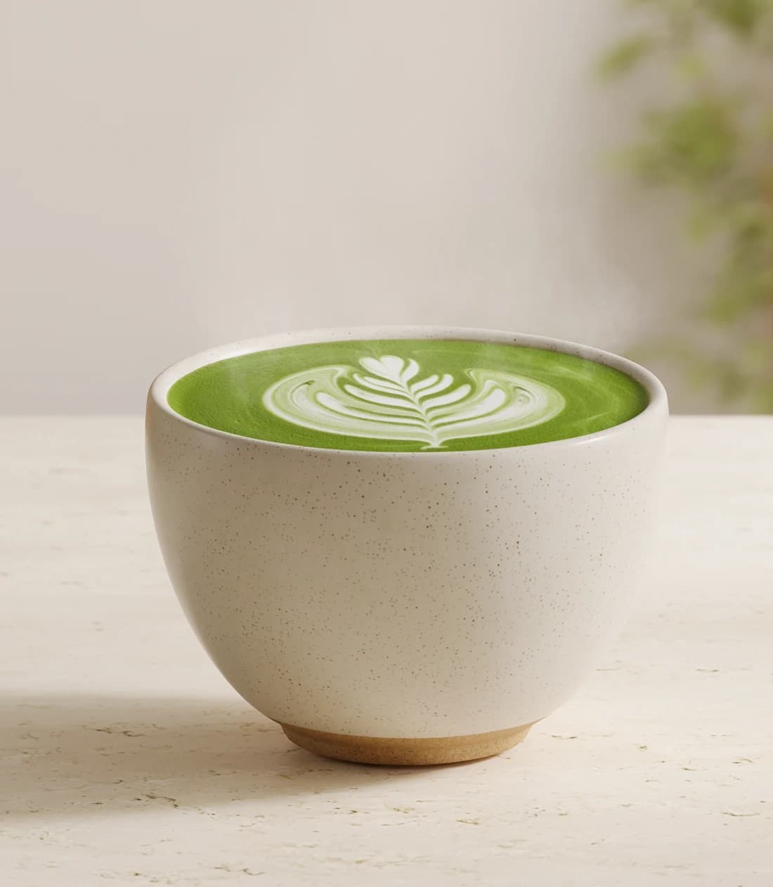 Matcha latte with white leaf latte art in a ceramic cup